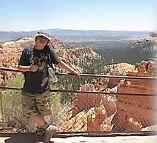 Christian, a young boy, poses on a bridge above a desert while on vacation.