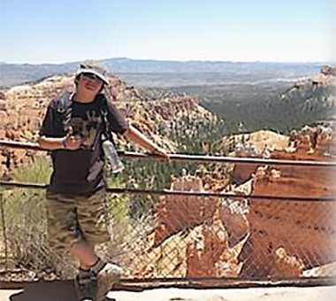 Christian, a young boy, poses on a bridge above a desert while on vacation.